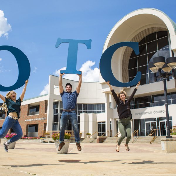 Student ambassadors jumping on the plaza holding the OTC Letters.