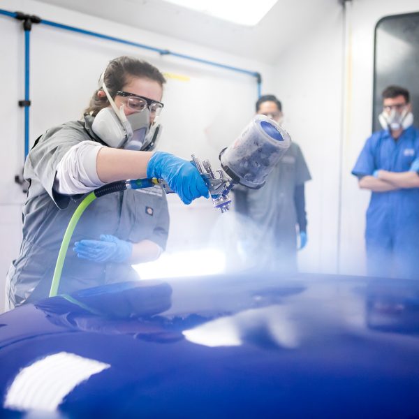 Auto Collision Repair Program student spraying a car hood.