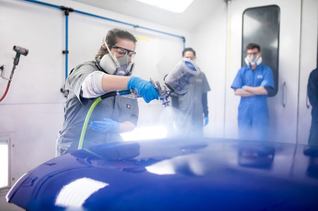 Auto Collision Repair Program student spraying a car hood.
