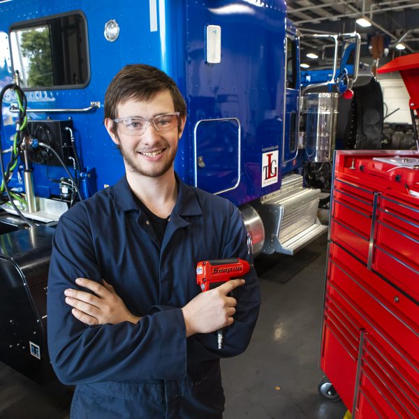 Diesel Technology program student stands holding a tool in the MHC Diesel Lab.