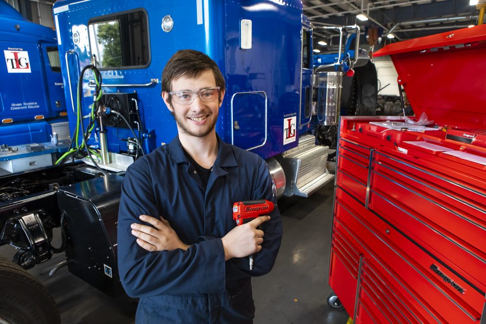 Diesel Technology program student stands holding a tool in the MHC Diesel Lab.