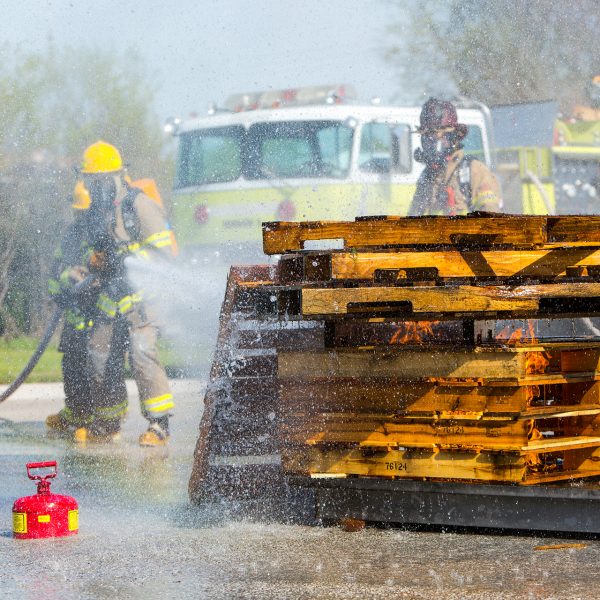 Fire Science Program students putting out a pallet fire with a fire hose.