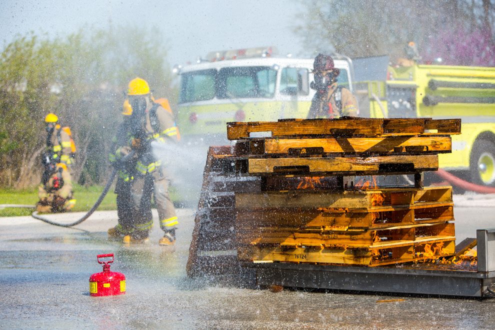 Fire Science Program students putting out a pallet fire with a fire hose.