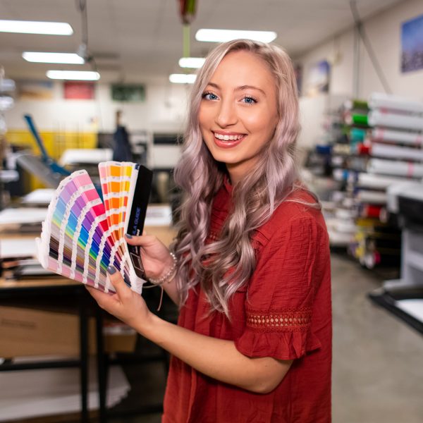 Graphic design student holds a pantone palette in a design lab.
