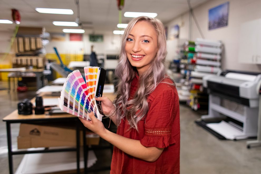 Graphic design student holds a pantone palette in a design lab.