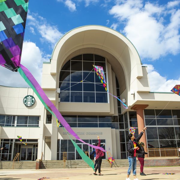 Students flying kites on the plaza in front of Information Commons.