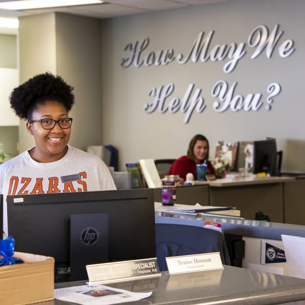 Student services specialist smiles as she welcomes students.
