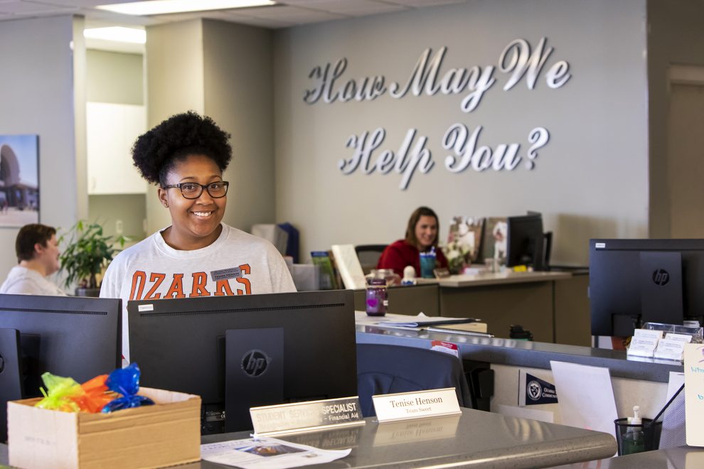 Student services specialist smiles as she welcomes students.
