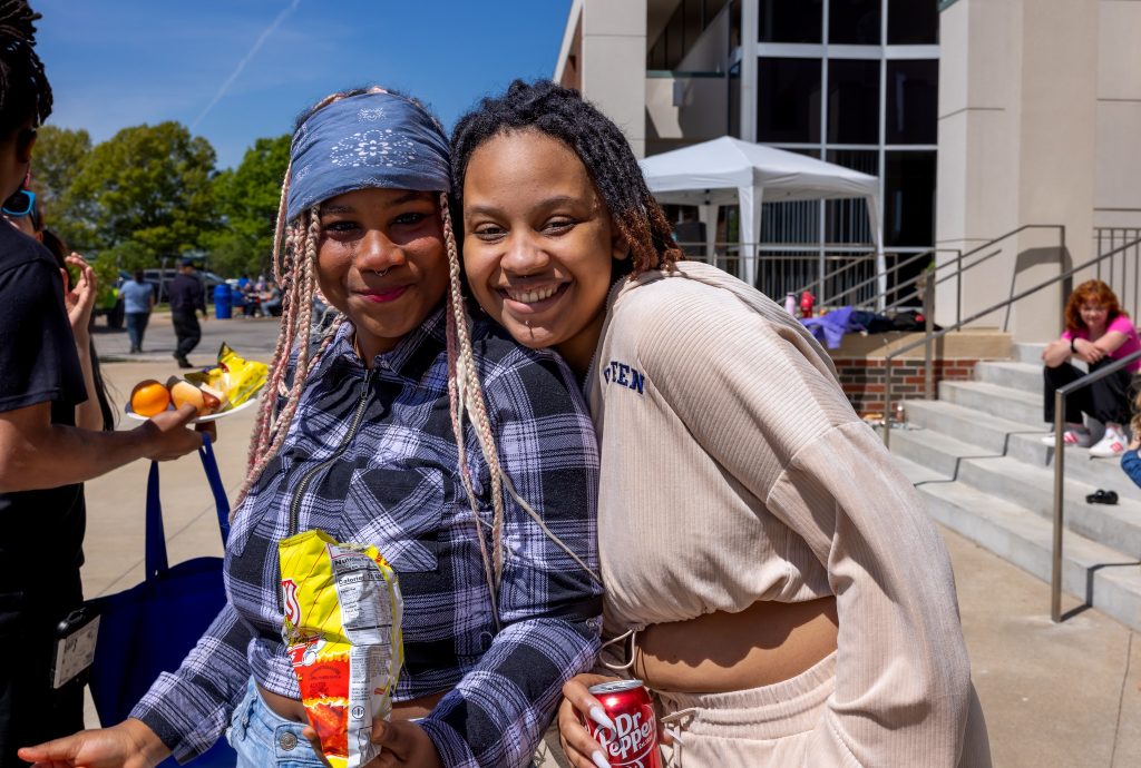 Students smiling with food and drink at picnic